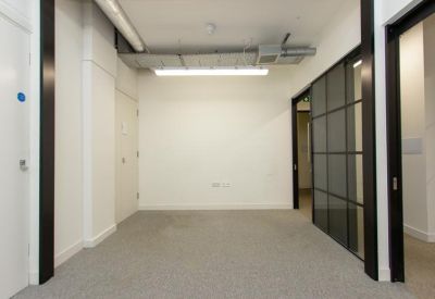 Brightly lit hallway area with white walls and glass partition office entrances.