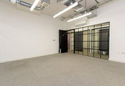 Spacious open plan office with industrial style exposed ceiling and glass partition wall.