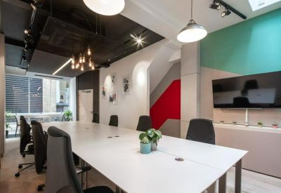 Spacious boardroom with a long white table, black chairs, and a feature red staircase.