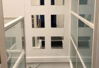 White hallway featuring mirrored wall accents and glass partition walls.