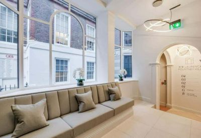 Reception waiting area featuring a long tufted bench seat beneath large arched windows.