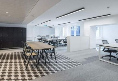 Spacious communal breakout area with a long wooden table and patterned tile flooring.