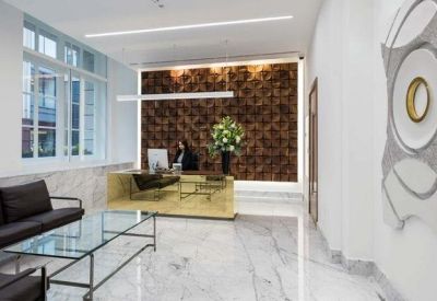 Bright reception area featuring marble floors, a gold desk, and a textured feature wall.