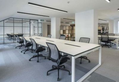 Modern open-plan office with white desks and ergonomic black chairs.