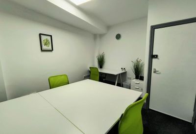 Meeting room with white tables, lime-green chairs, and potted plants.