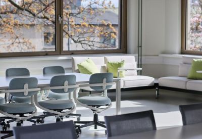 Sunlit communal seating area with white sofas and lime green accent pillows.