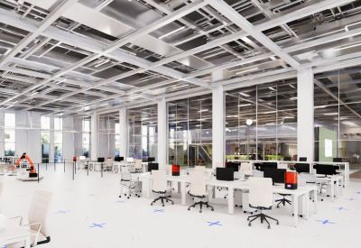 Modern open-plan office with white desks, industrial ceilings, and robotic equipment.