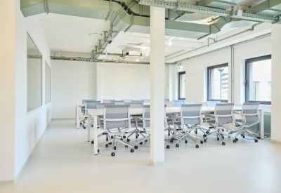 Large, bright training room with white tables and ergonomic grey chairs.