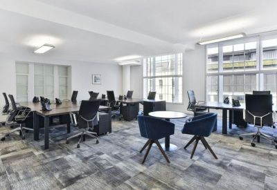 Open-plan office with dark wood desks and ergonomic black mesh chairs.