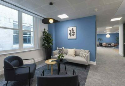 Lounge area featuring a blue accent wall, grey sofa, and mid-century modern armchairs.