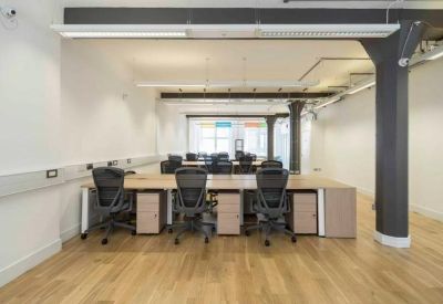 Large open-plan office with rows of desks, ergonomic chairs, and dark grey structural pillars.
