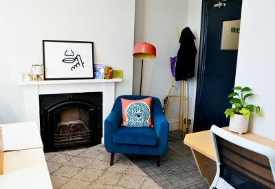 Blue armchair in a cozy corner with a fireplace and unique wall art.