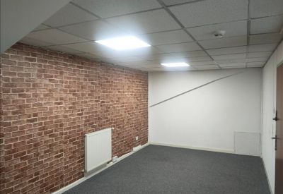 Private office featuring a brick-effect feature wall and white radiator.