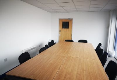Spacious meeting room with a large wooden table and black chairs.