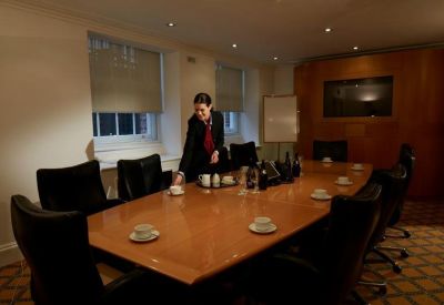 Traditional boardroom with a large wooden table and black leather chairs.