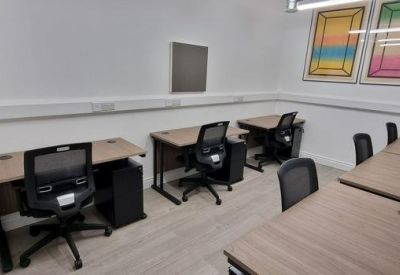 Shared office space with individual desks, ergonomic chairs, and colourful wall art.