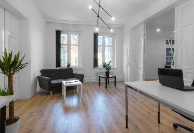 Communal lounge area with a black sofa, white coffee table, and indoor plants.