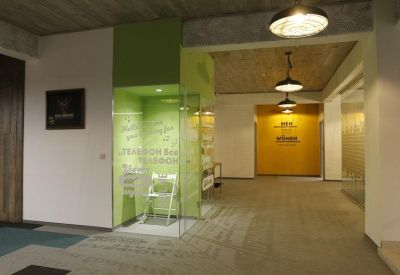 Modern lobby area featuring a bright green glass-walled booth and a yellow accent wall in the distance.