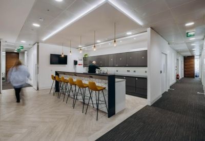 Modern office kitchen and breakfast bar with yellow stools and pendant lighting.