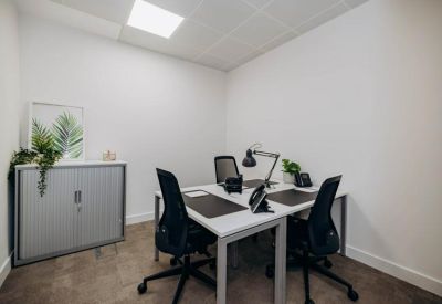 Private three-person office suite with white desks and black ergonomic chairs.