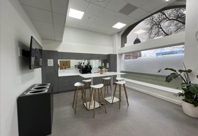 Communal kitchen and breakout area with high stools and a coffee station.