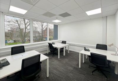 Bright office with three white desks and views of surrounding trees.