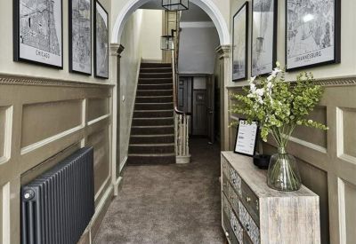 Elegant entrance hallway with wood paneling, decorative coving, and framed architectural sketches.