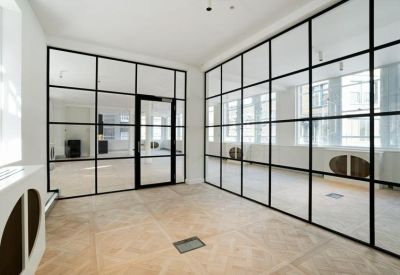 Minimalist corridor featuring black-framed glass partitions and light wood floors.