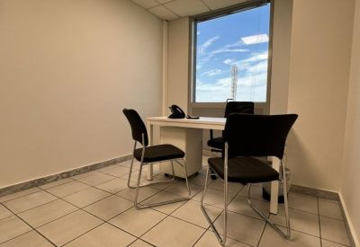 Private office with a white desk and a large window showing blue sky.