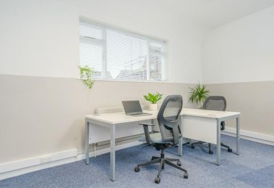 Natural light-filled corner office with white desks and blue carpeting.