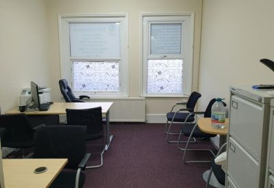 Professional four-person office suite with desks, ergonomic chairs, and large windows.