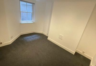Private office space with dark grey carpeting and a large sash window.