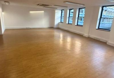 Wide open-plan office floor with light wood laminate flooring.