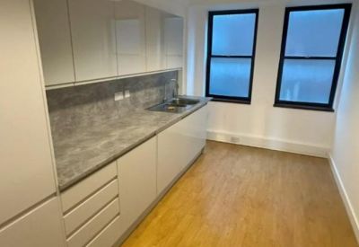 Modern galley kitchen with white cabinetry and grey stone countertops.