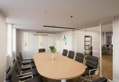 Executive boardroom with a long wooden table and black leather chairs.