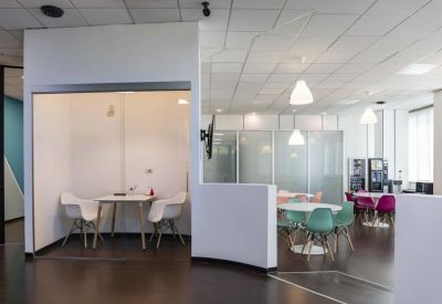 Semi-private office pod with a small white table and two modern armchairs.