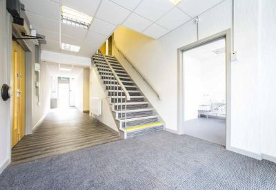 Bright lobby area featuring a central staircase, grey carpeting, and neutral walls.