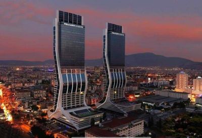 Exterior view of the modern, curved twin towers of Folkart Towers against a sunset sky.