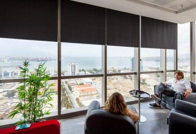 Bright communal lounge area with leather armchairs and a panoramic coastal view.