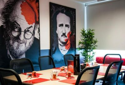 Meeting room with large artistic portraits and red table settings.