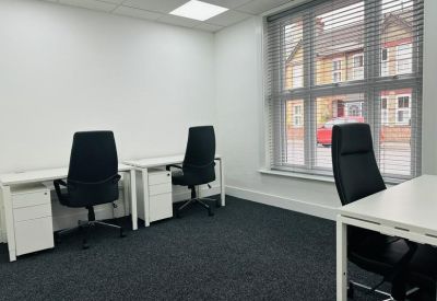 Bright three-person office suite with white desks and black ergonomic chairs.