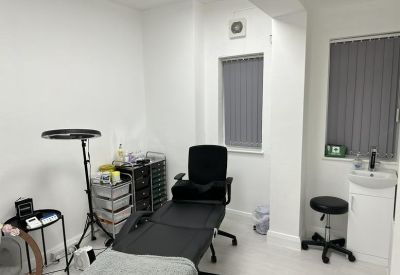 Clinical treatment room with adjustable black bed, sink, and medical trolley.