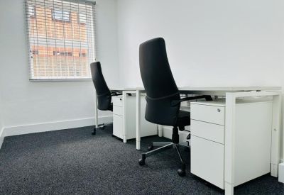 Two-person workspace with white pedestal desks and window blinds.
