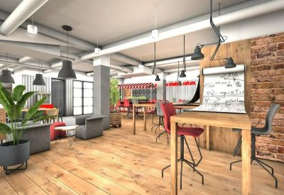 Open-plan workspace with wooden floors, industrial lighting, and a brick feature wall.