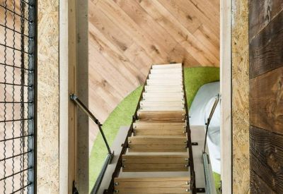 Looking up through a ceiling hatch at a wooden ladder and attic entrance.
