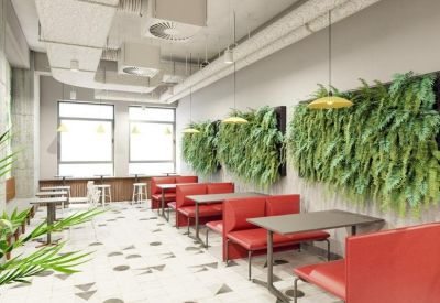 Spacious communal dining area with red booths and lush green vertical garden walls.