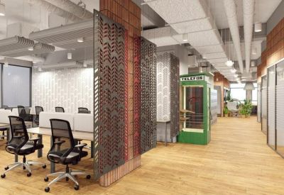 Open-plan office space featuring a green phone booth, mesh partitions, and wooden flooring.