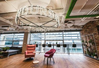 Spacious lounge with a large circular neon light fixture and colorful armchairs.