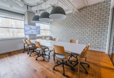 Meeting room with a white conference table, grey dome pendant lights, and patterned wallpaper.