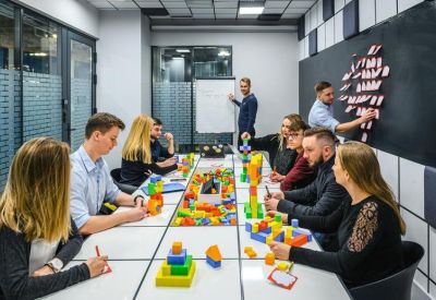Creative meeting room where a team works with colorful building blocks on a long white table.